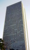 Ground-level view of two grey, rectangular building faces perfectly lined with columns of windows