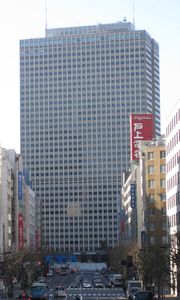 A street acts as a corridor, leading directly to the rectangular, window-dotted facade of the Kasumigaseki Building