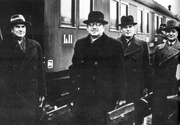 A group of four men wearing hats and a train behind.