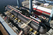 Aerial photograph of a submarine removed from the water in a dock. Flags and banners decorate the submarine.