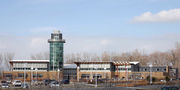 Across a parking lot is a two-story building with a circular tower that is offset from the center of the building.