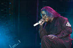 A man wearing a mask while singing into a microphone.